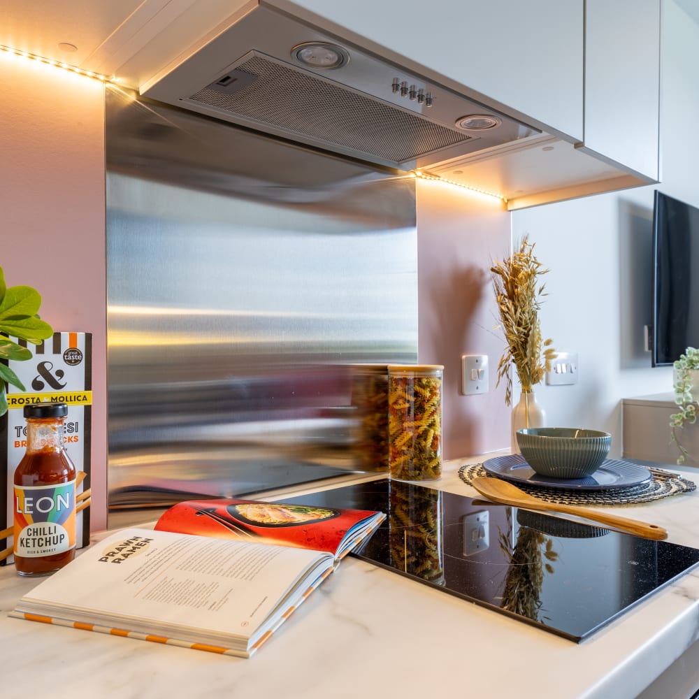 Cooking area inside a kitchenette, with a hob, cooking book and ingredients