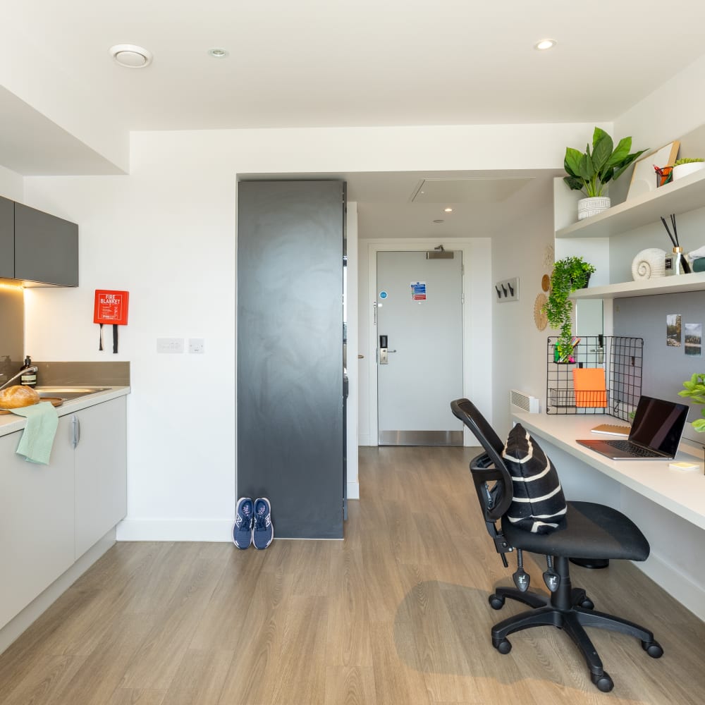 Student room with a white desk and a grey kitchenette