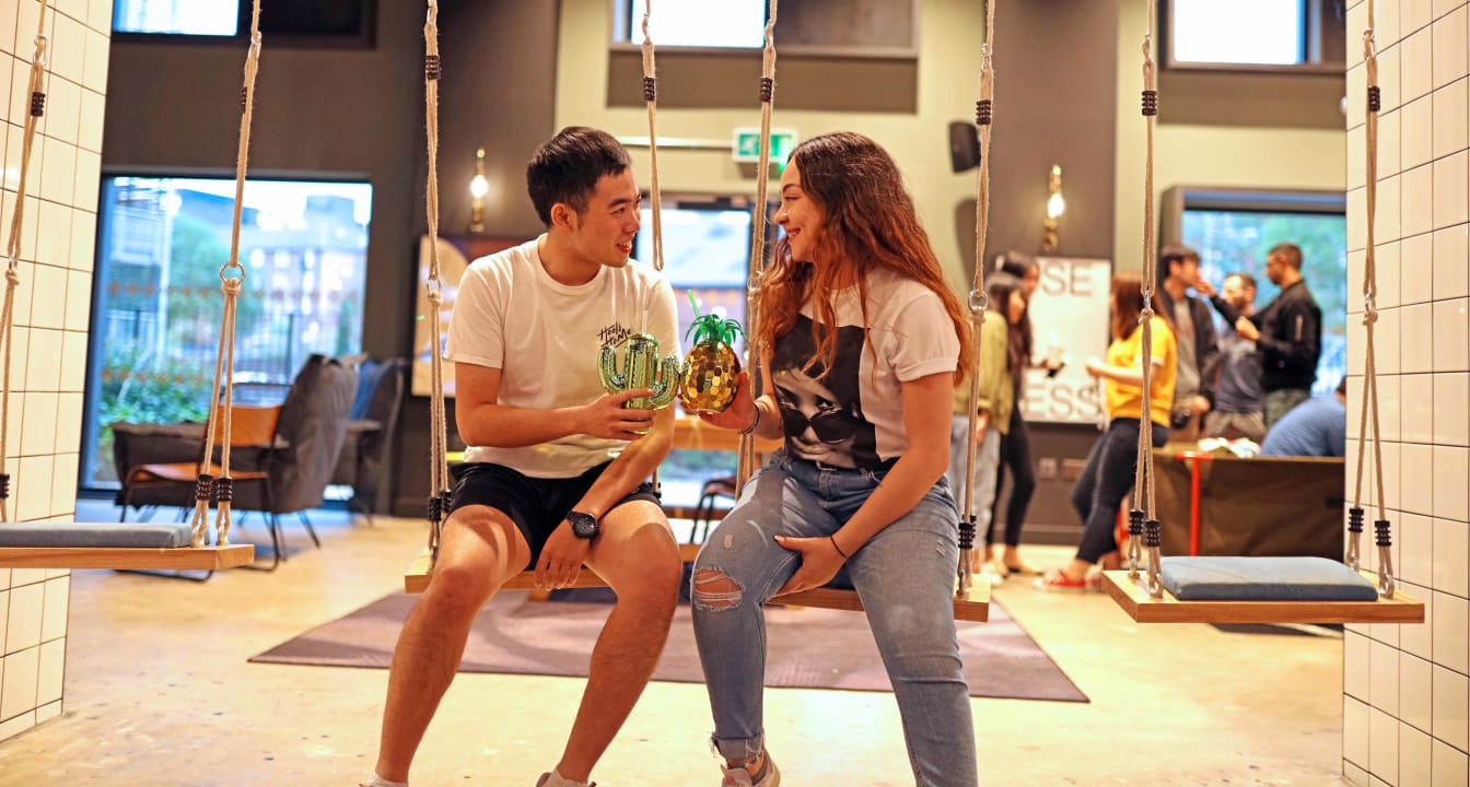 Two students share a drink in a social space at their student accommodation