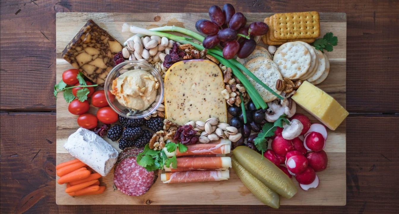 Charcuterie board with grapes, crackers, cheese, vegetables and meat