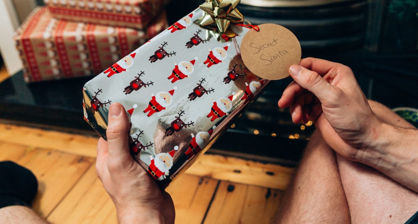 Man holds a gift with 'Secret Santa' written on the label