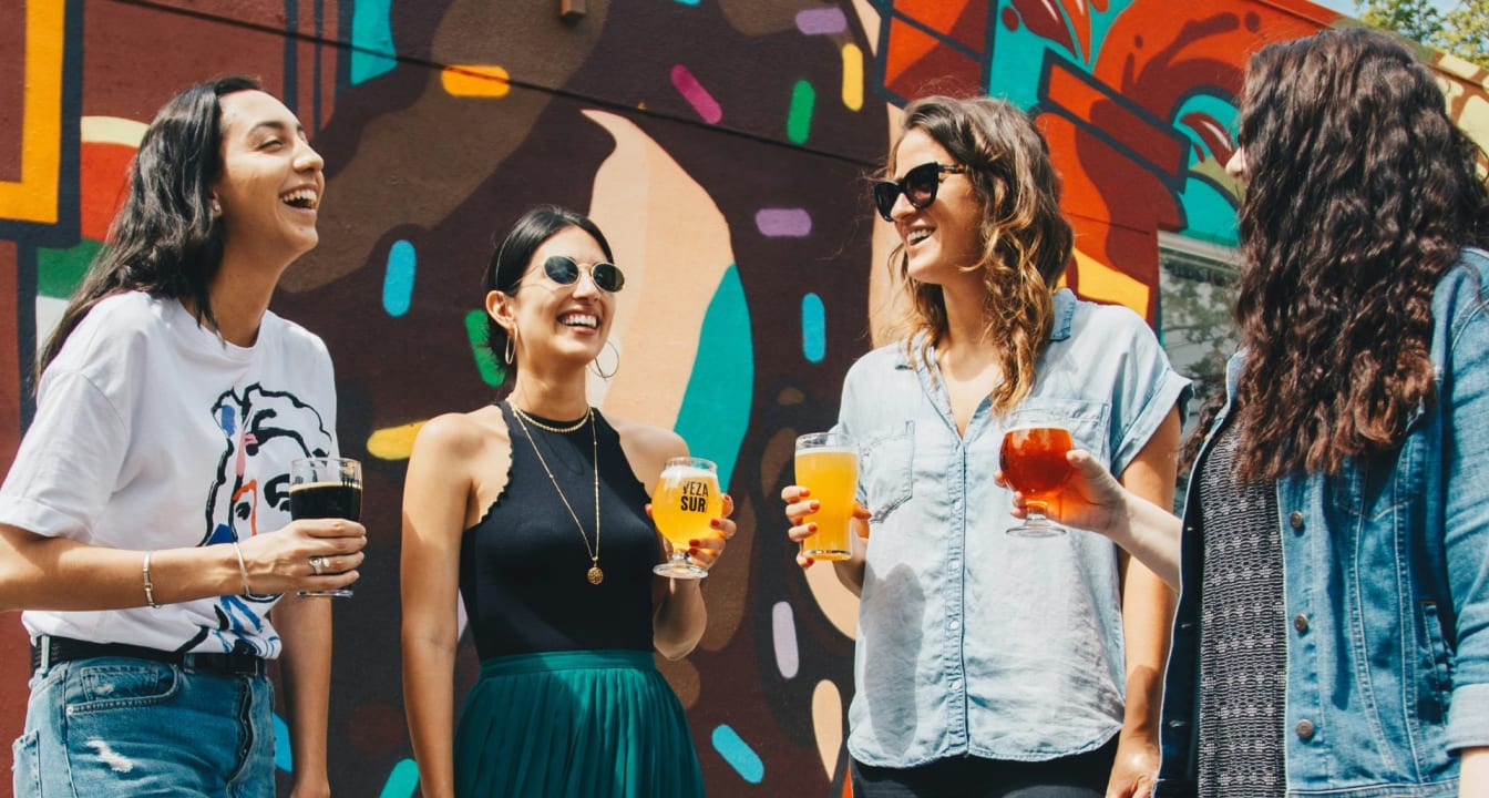 Four students stand with beer pints against painted background