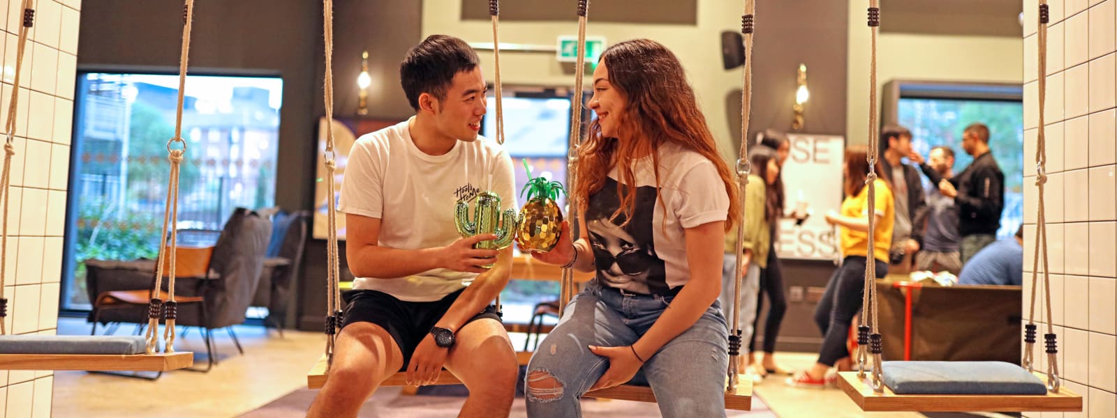 Two students share a drink in a social space at their student accommodation