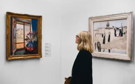 Student stands between two paintings in an art gallery