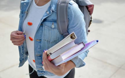 Student holds stack of four books