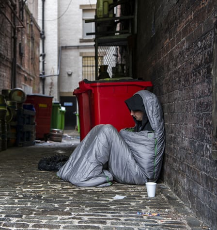 Man in sleeping bag in alley way