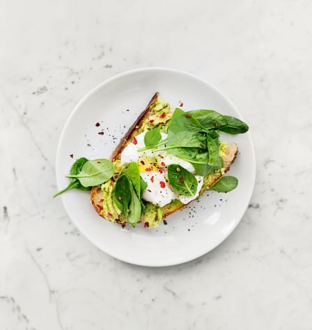 A plate of avocado toast on a marble counter