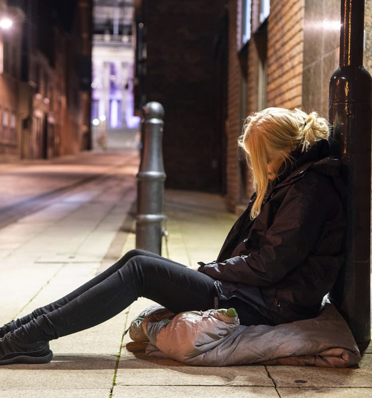 Women say on the floor leaning on a lamppost