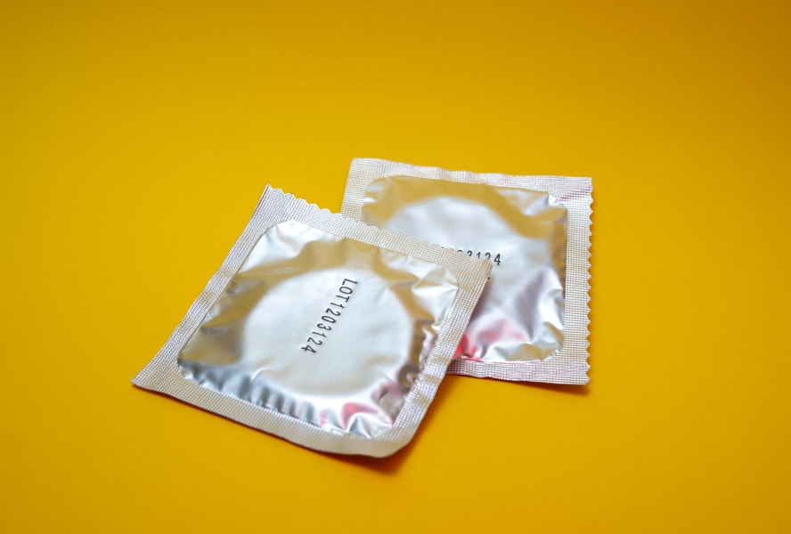 Two condoms on a yellow background