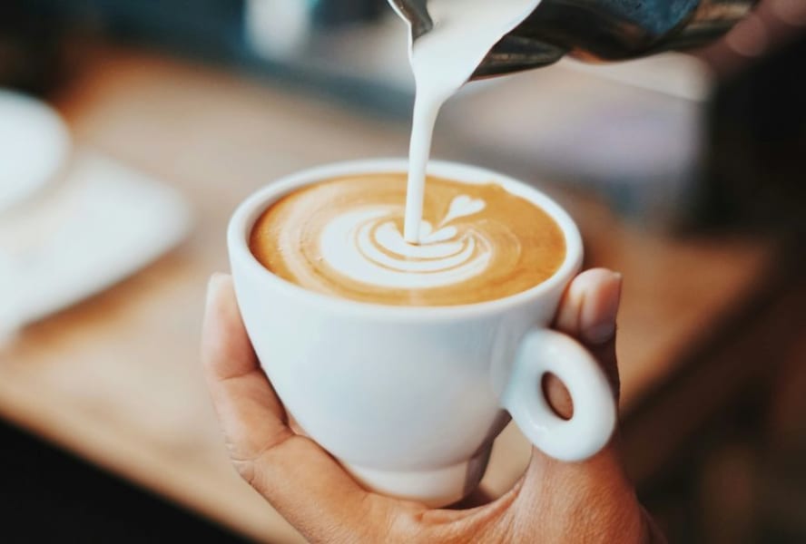 Milk being poured into a freshly made coffee.