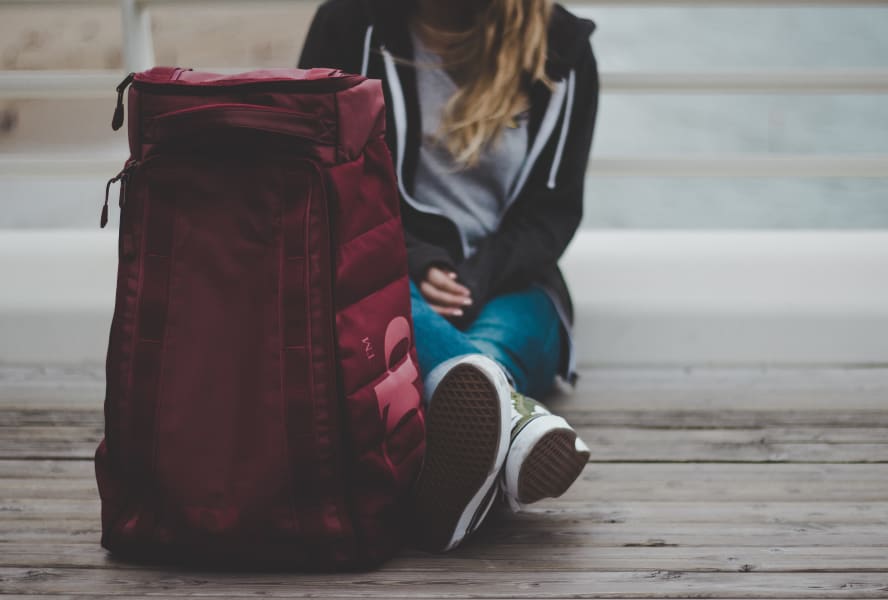 International student sits on floor with a bag of luggage