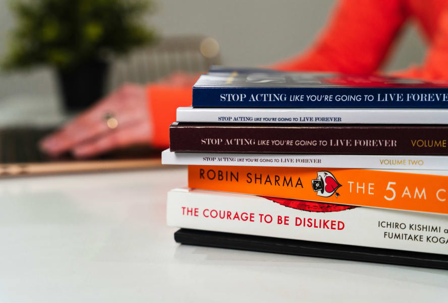 Stack of books including 'Stop Acting Like You're Going to Live Forever', 'The 5am Club' and 'The Courage to be Disliked'