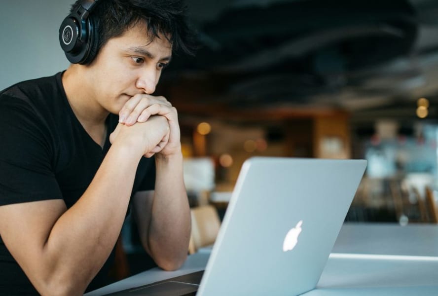 Student revising on a laptop with headphones on