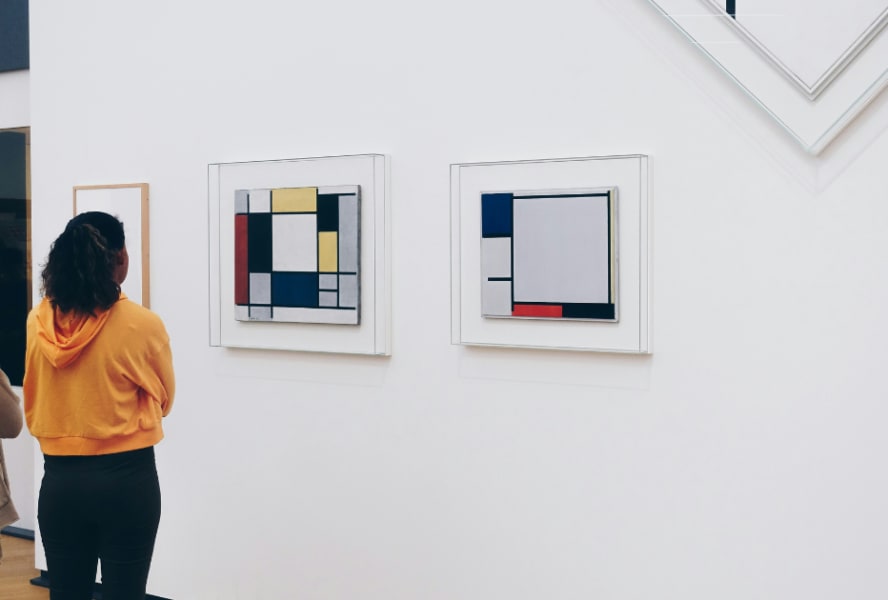 Male and female student stand in front of abstract art piece in gallery