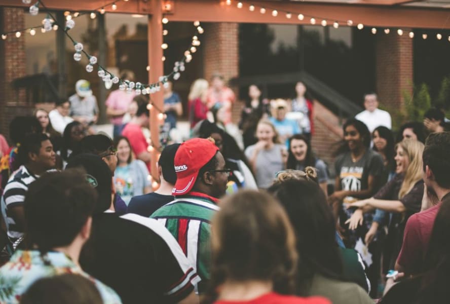 Crowd of students party outdoors under fairy lights