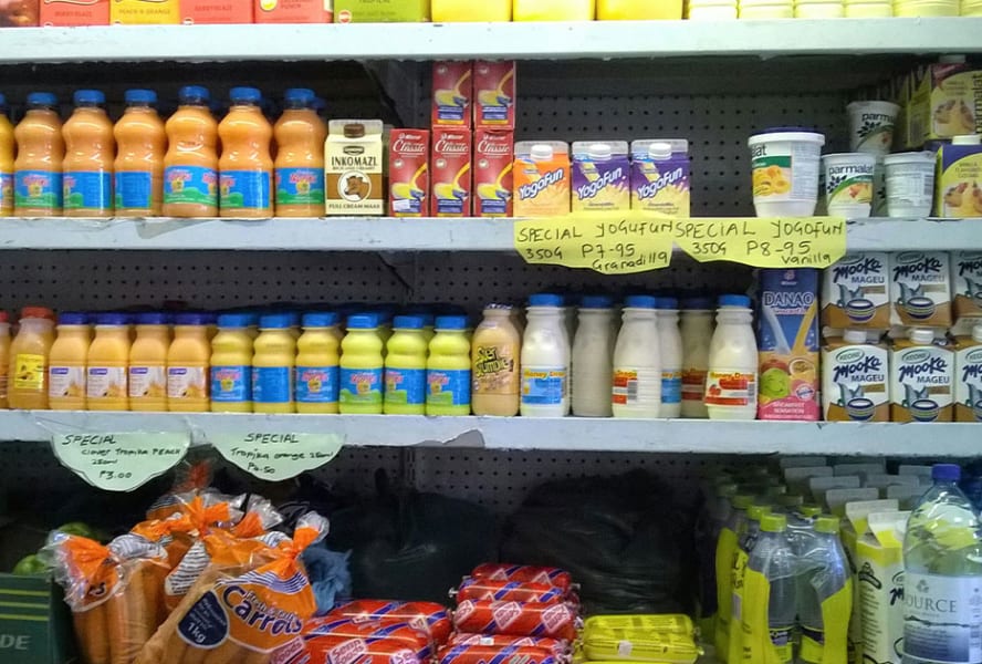 Supermarket shelves with milk, yoghurt, juices, carrots and water.