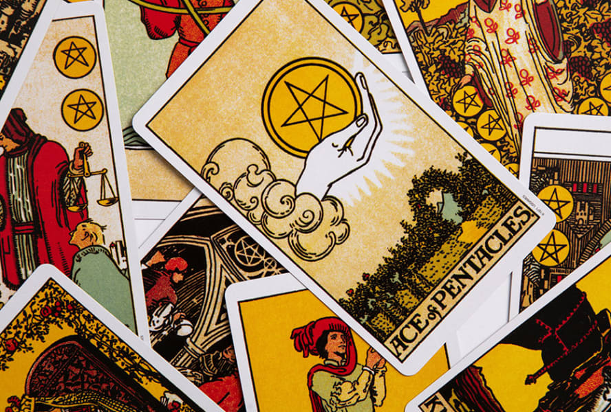 Stack of tarot cards with ace of pentacles scattered on top