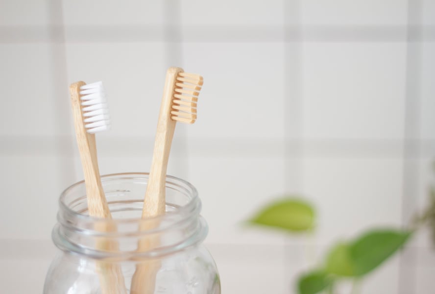 Two bamboo toothbrushes sit in a jar