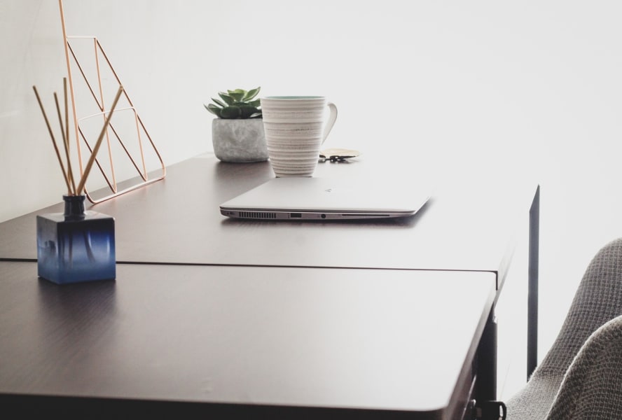 Diffuser, laptop, mug and plant on a wooden desk