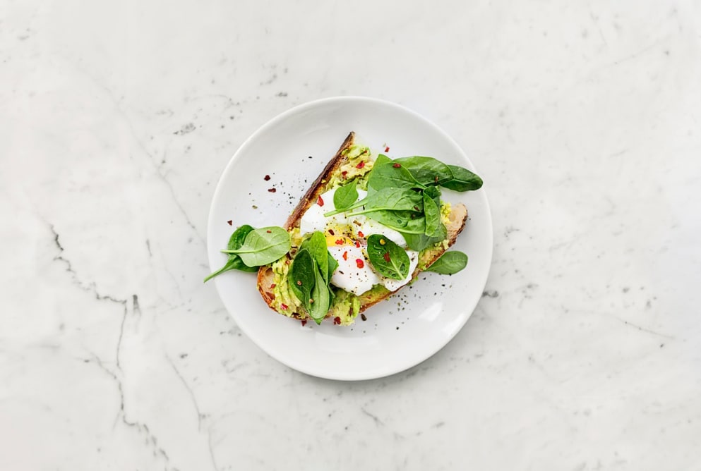 A plate of avocado toast on a marble counter