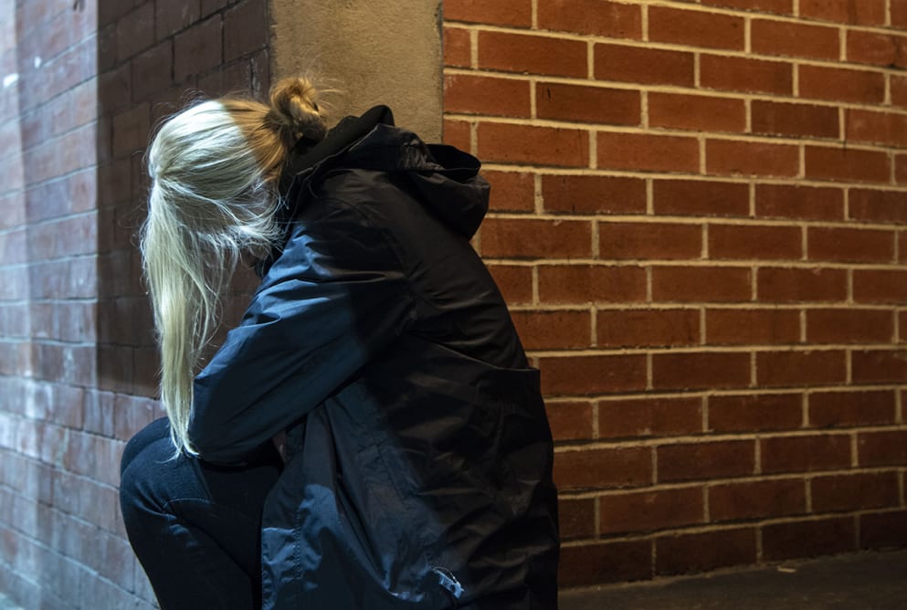 A woman is sat on a step with her hair falling over her face.