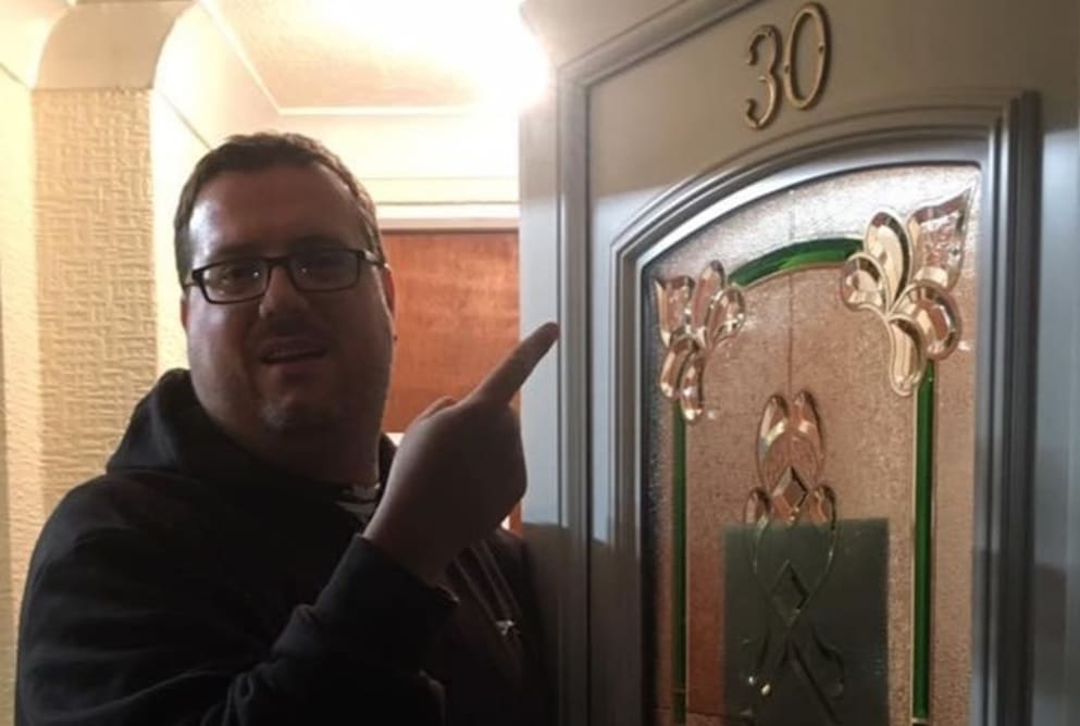 A man named Ricky standing outside and pointing to a door with the number 30 on it