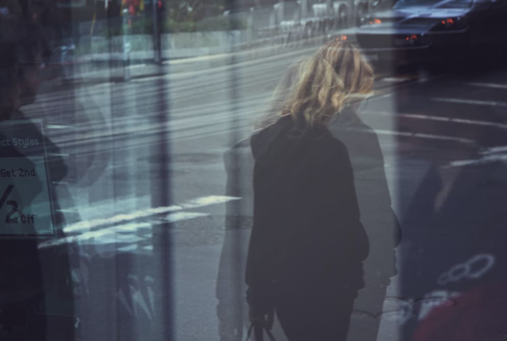 woman walking across a street. The image is blurred and the woman is looking away.