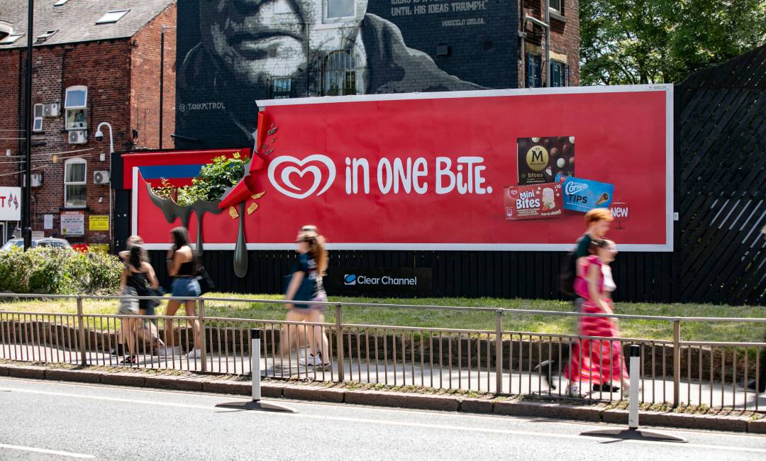 people walking past large OOH poster site with Walls advert