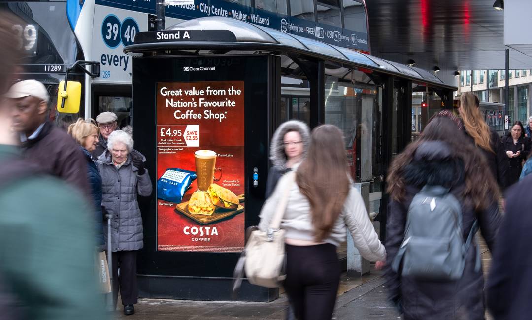 Digital screen on a bus stop showing advert for Costa Coffee on a busy high street
