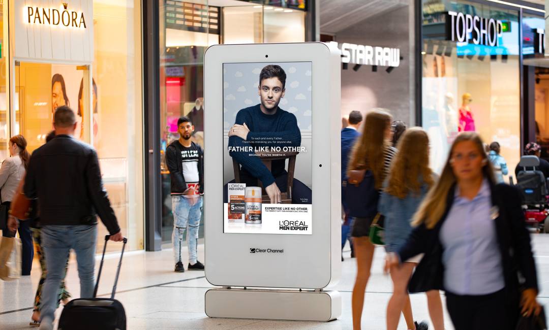 Loreal advert on digital screen in shopping mall with people walking past