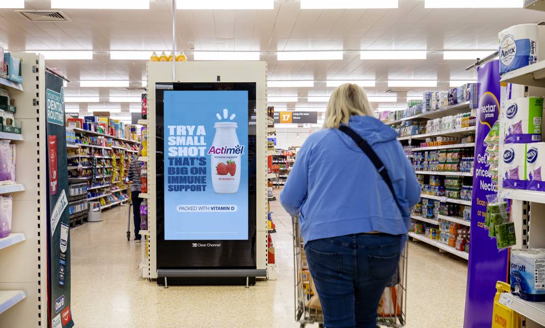 A customer in Sainsbury's walking down a shopping isle past a Sainsbury's Live Actimel advertisement