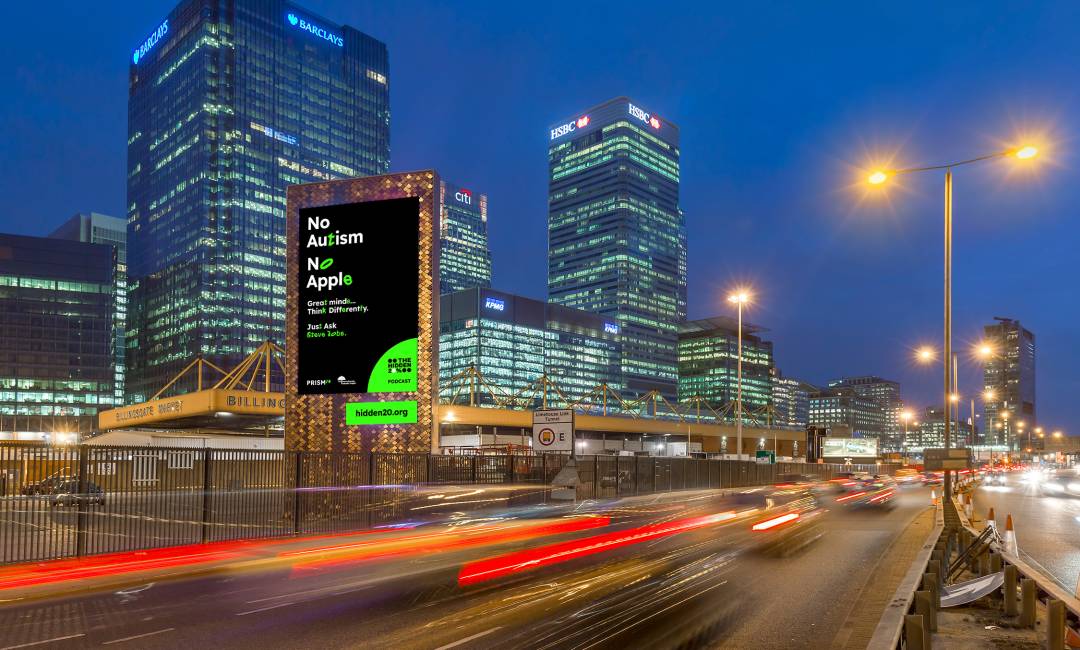 An advert promoting The Hidden 20% at Billingsgate Tower on a busy road by Canary Wharf at night