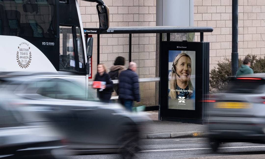 Digital bus shelter screen with bus, cars and people going past