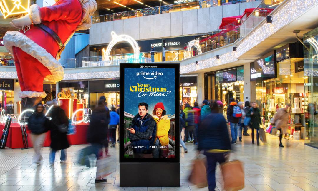 A Malls Live screen displaying a Christmas advert inside a busy shopping centre surrounding by Christmas decorations