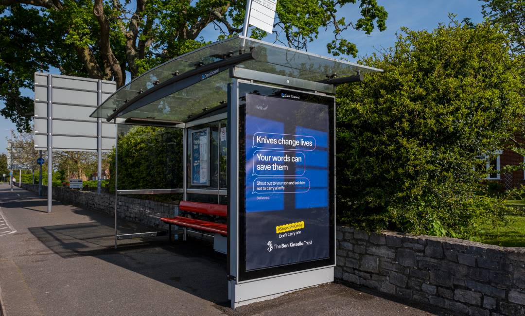 A bus shelter featuring a digital screen displaying the Ben Kinsella campaign messaging, in Bournemouth, during the day