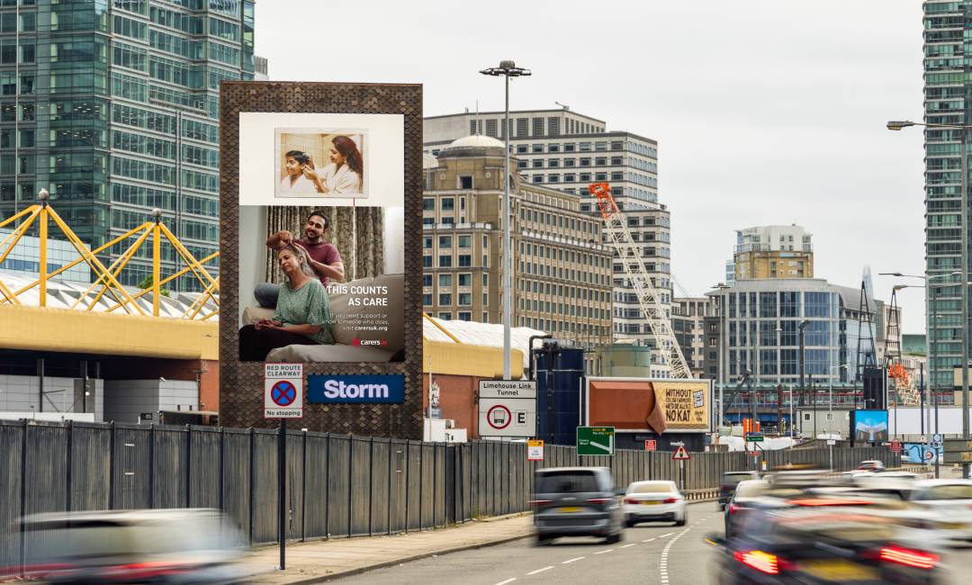 ‘This Counts As Care’ campaign advertisement for Carers UK featured on a Storm billboard by a busy roadway as cars pass by in the middle of the day.