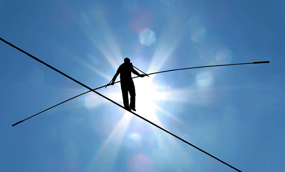 A shadow of a tightrope walker with a sunny sky in the background