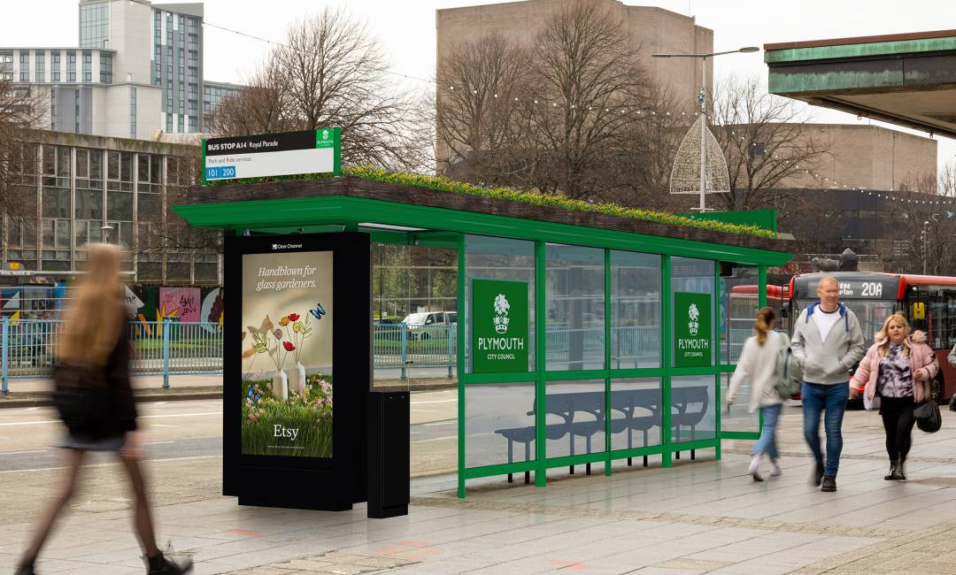 A living roof bus stop with people walking on the sidewalk.