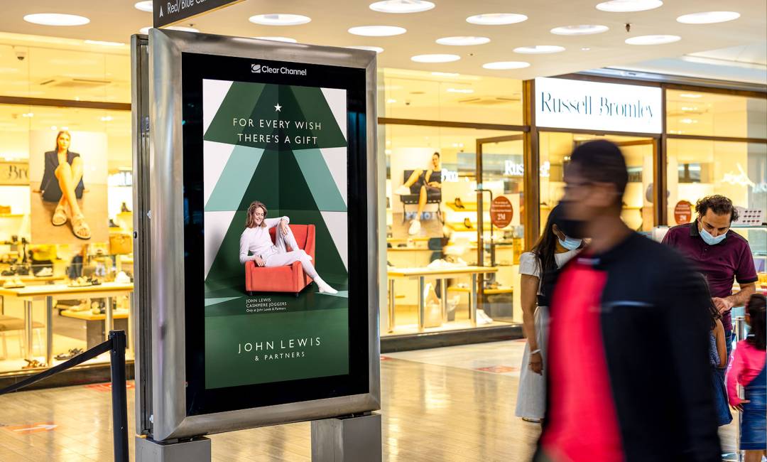 Digital screen in a shopping mall outside Russell & Bromley showing a John Lewis advert