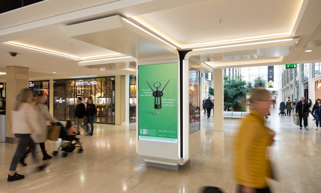 Clear Channel's digital advertising screen in Centre MK shopping mall showing a John Lewis ad with people walking past