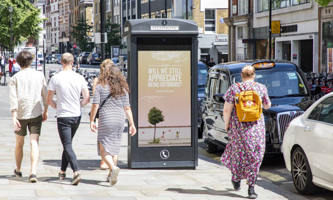 Digital phone box screen on a busy high street showing Our Second Chance Campaign