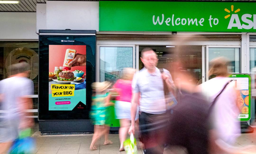 Burger sauce advert on a digital screen outside a supermarket with the tagline of 'flavour up your BBQ'