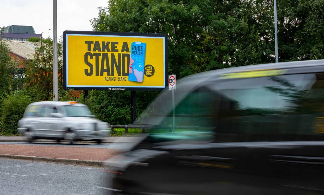 Billboard screen over busy road displaying yellow image with blue carton