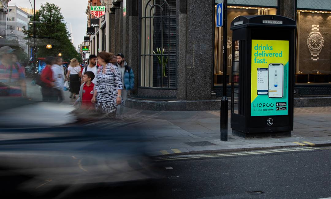 Clear Channel phone Kiosk on a busy high street showing advert for LIQROO app