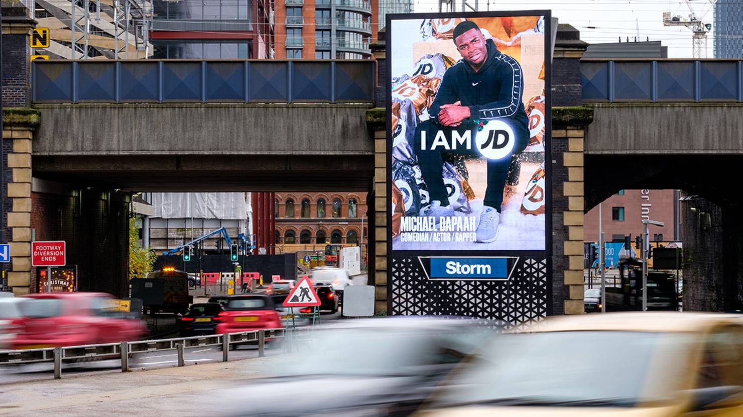 JD Sports Christmas ad featuring Michael Dapaah comedian, actor and rapper on large digital portrait screen