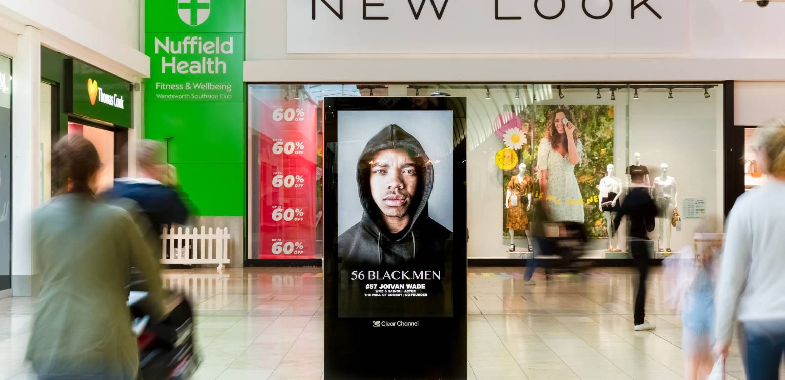 Digital screen outside New Look in a busy shopping mall showing 56 Black Men Campaign