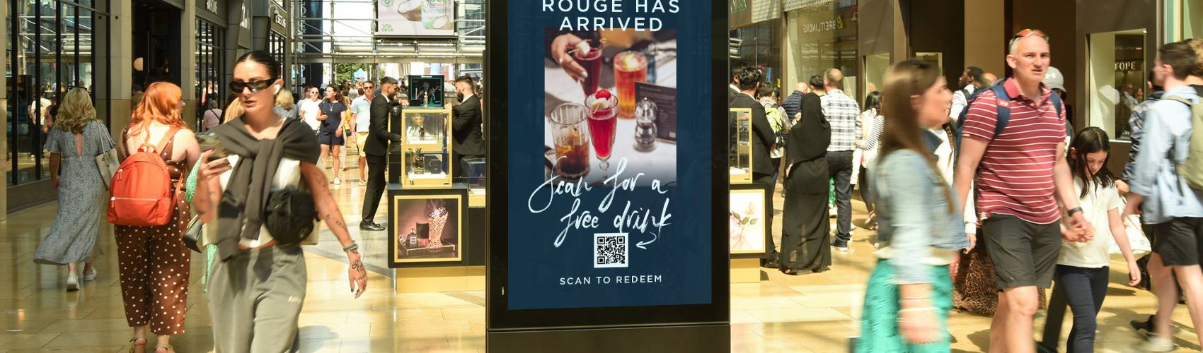 Cafe advert on a digital mall poster with a QR code to 'scan for a free drink'