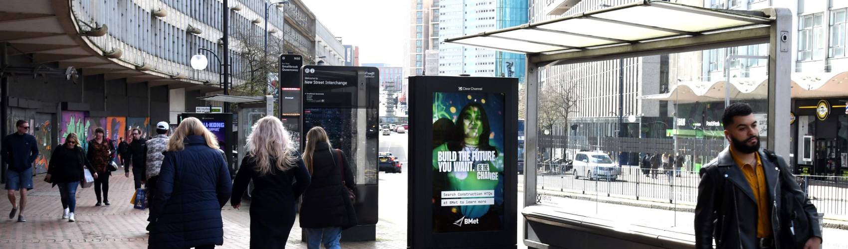 BMet ad campaign displaying on an Adshel Live bus stop digital screen with people walking by