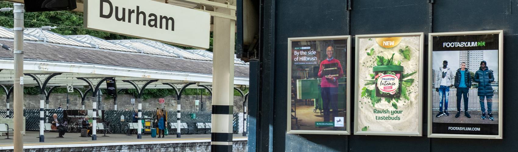 Set of 3 small poster adverts on an outdoor train station concourse