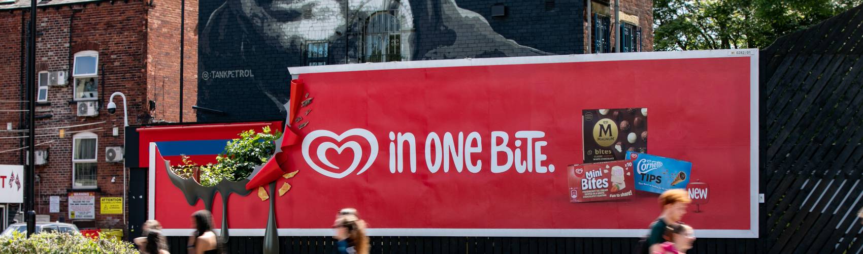 people walking past large OOH poster site with Walls advert